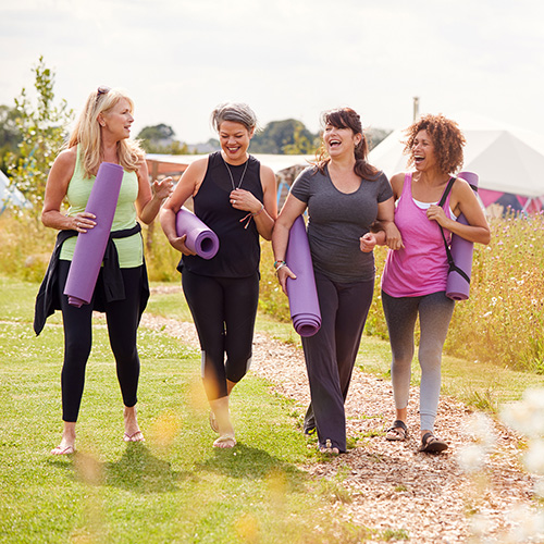 A group of women outside, walking together, holding yoga mats